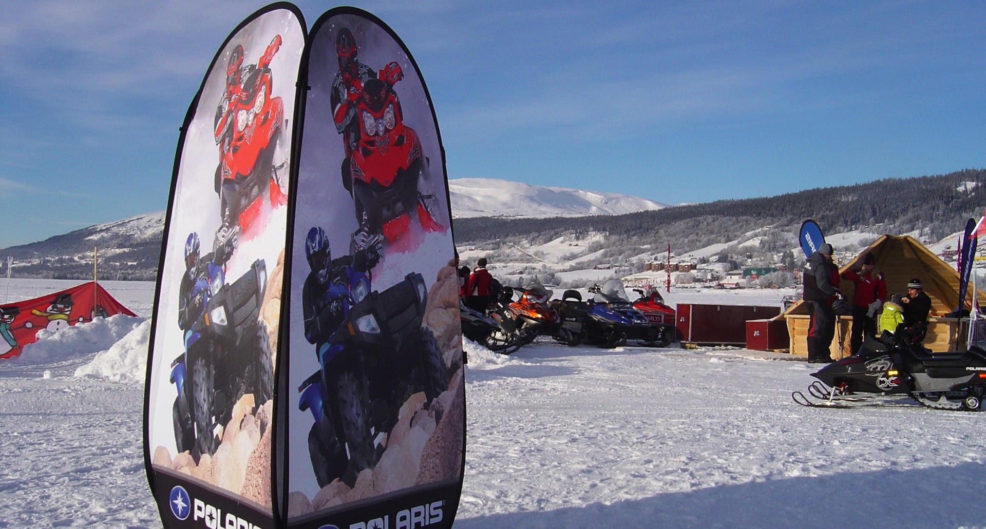 Werbesäule Quicktower Polaris mit Bildern von Schneemobilen und Fahrern in einer winterlichen Landschaft.