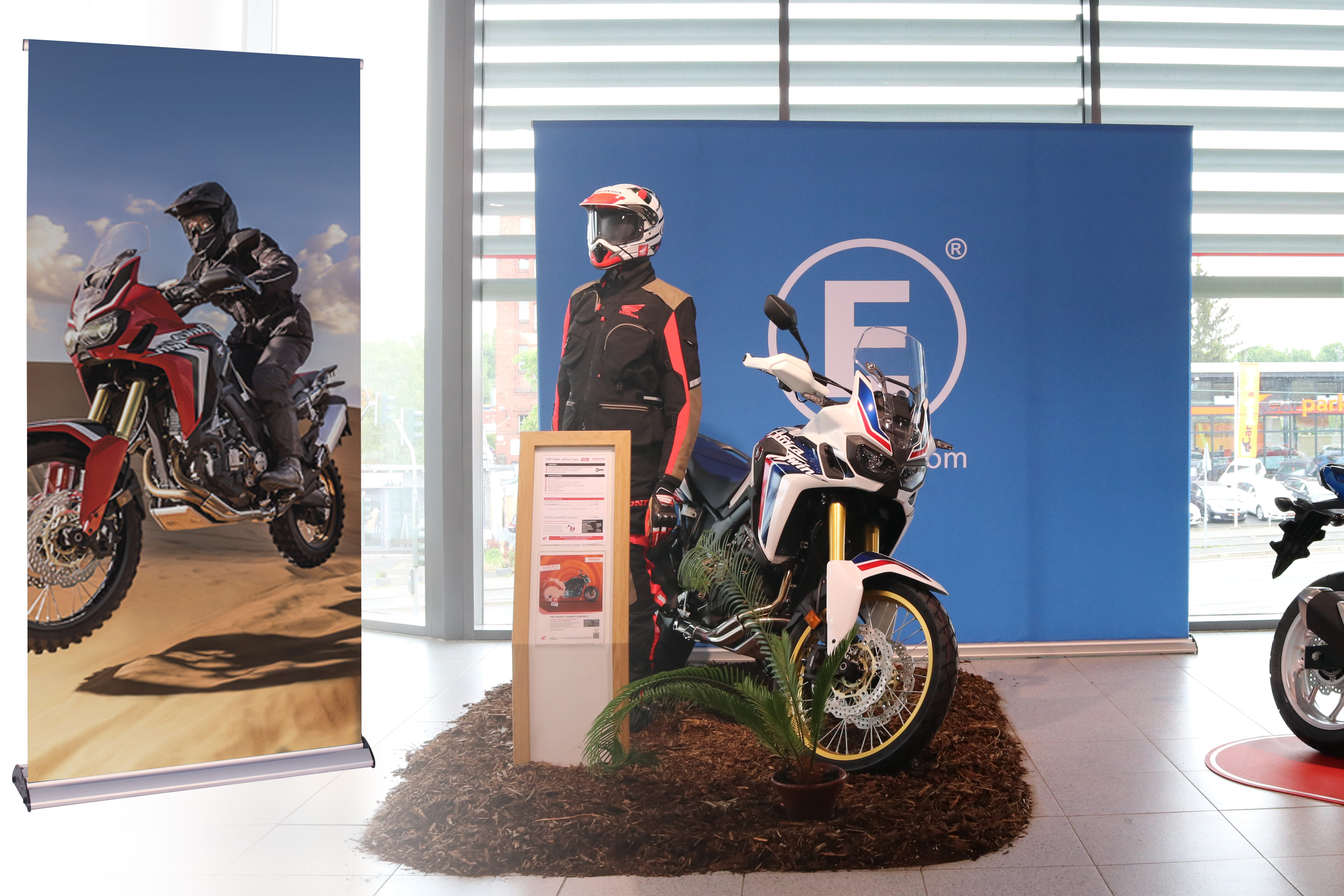 Produktpräsentation des Easywall Flex Honda Rollup mit einem Motorrad und einem Bekleidungsmodell in einem Ausstellungsraum.