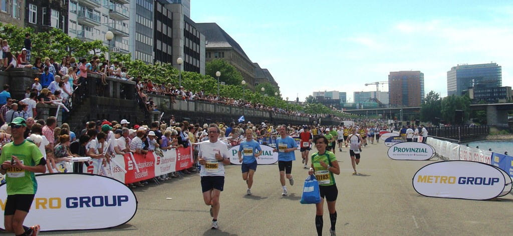 Läufer beim Marathon, umgeben von Zuschauern und Werbebanden der Metro Group.