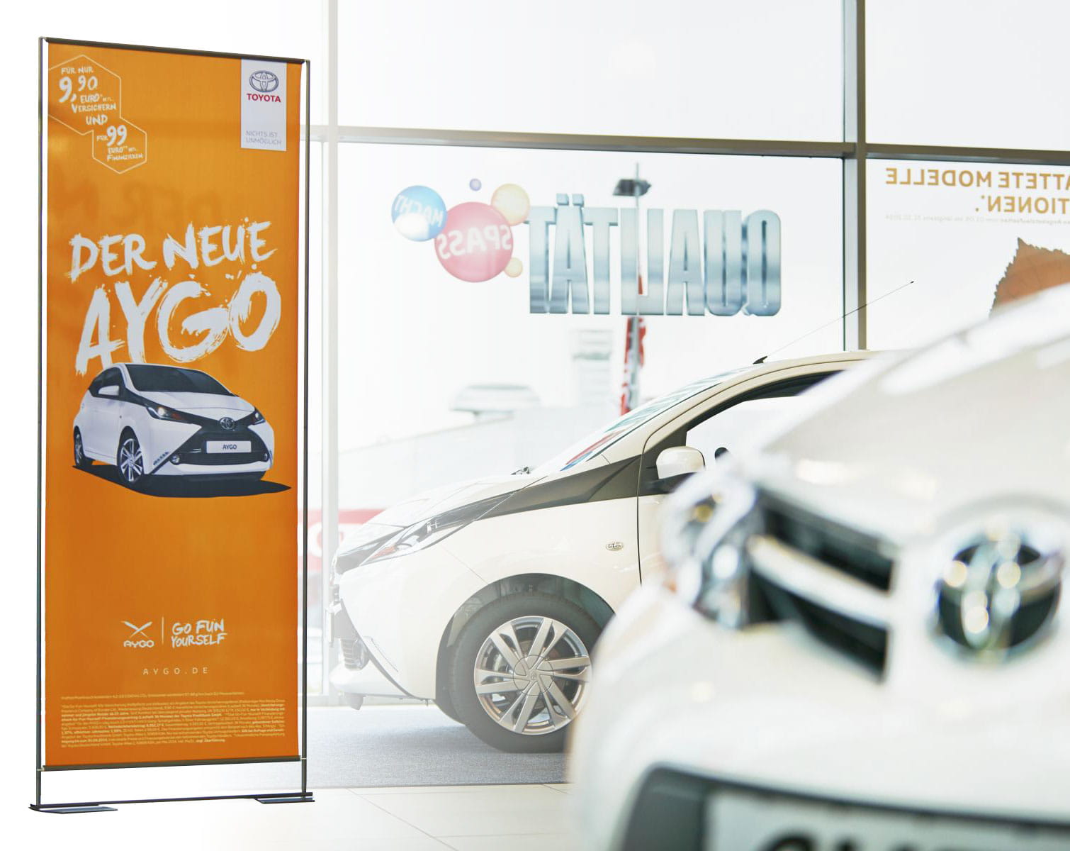 Roll-Up-Stand von ENTDECKER mit Werbung für den neuen Toyota Aygo im Autohaus.