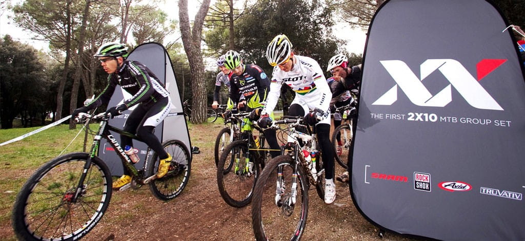 Fahrradfahrer starten an einer Werbebande für das Produkt Quickboard.