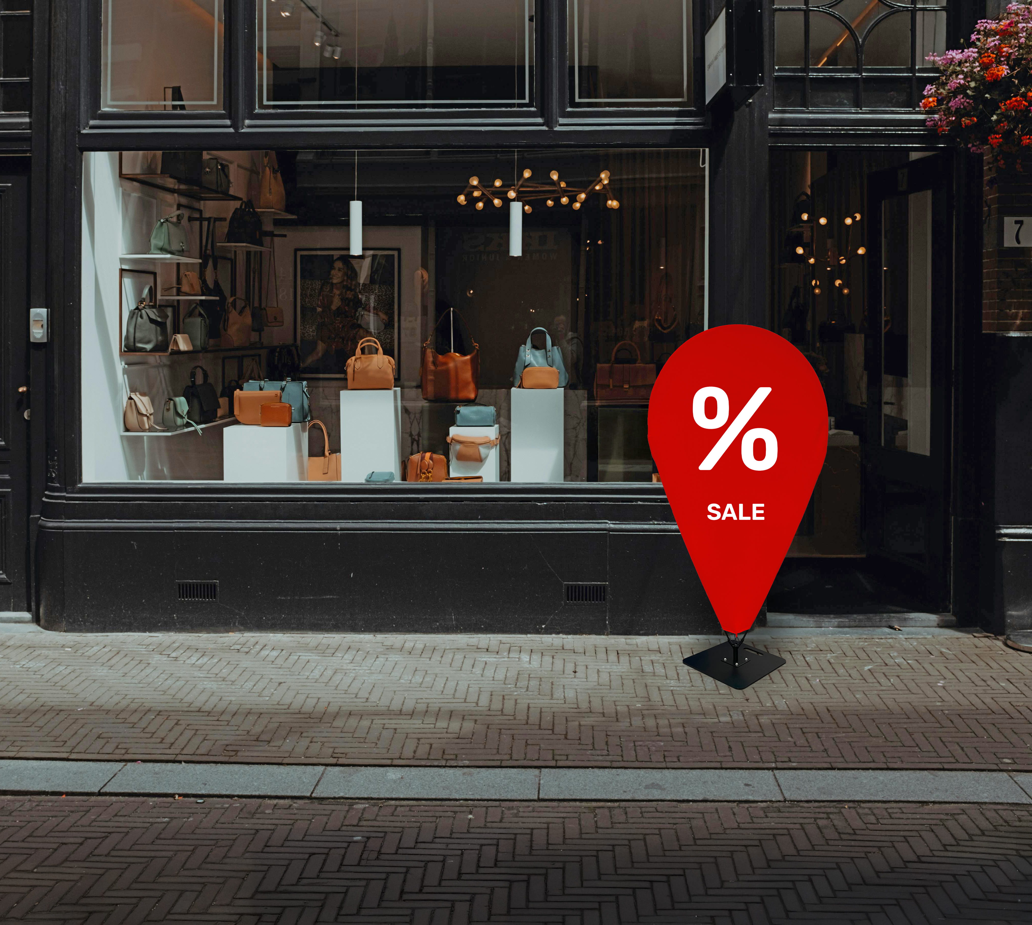 Schaufenster eines Geschäfts mit Taschen, das einen roten Sale-Aufsteller zeigt.